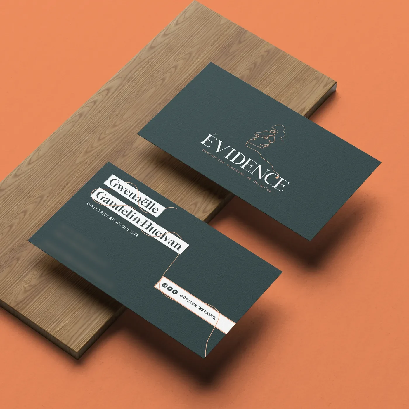 Cartes de visite Évidence vert sombre posées sur une planche de bois, sur fond orange