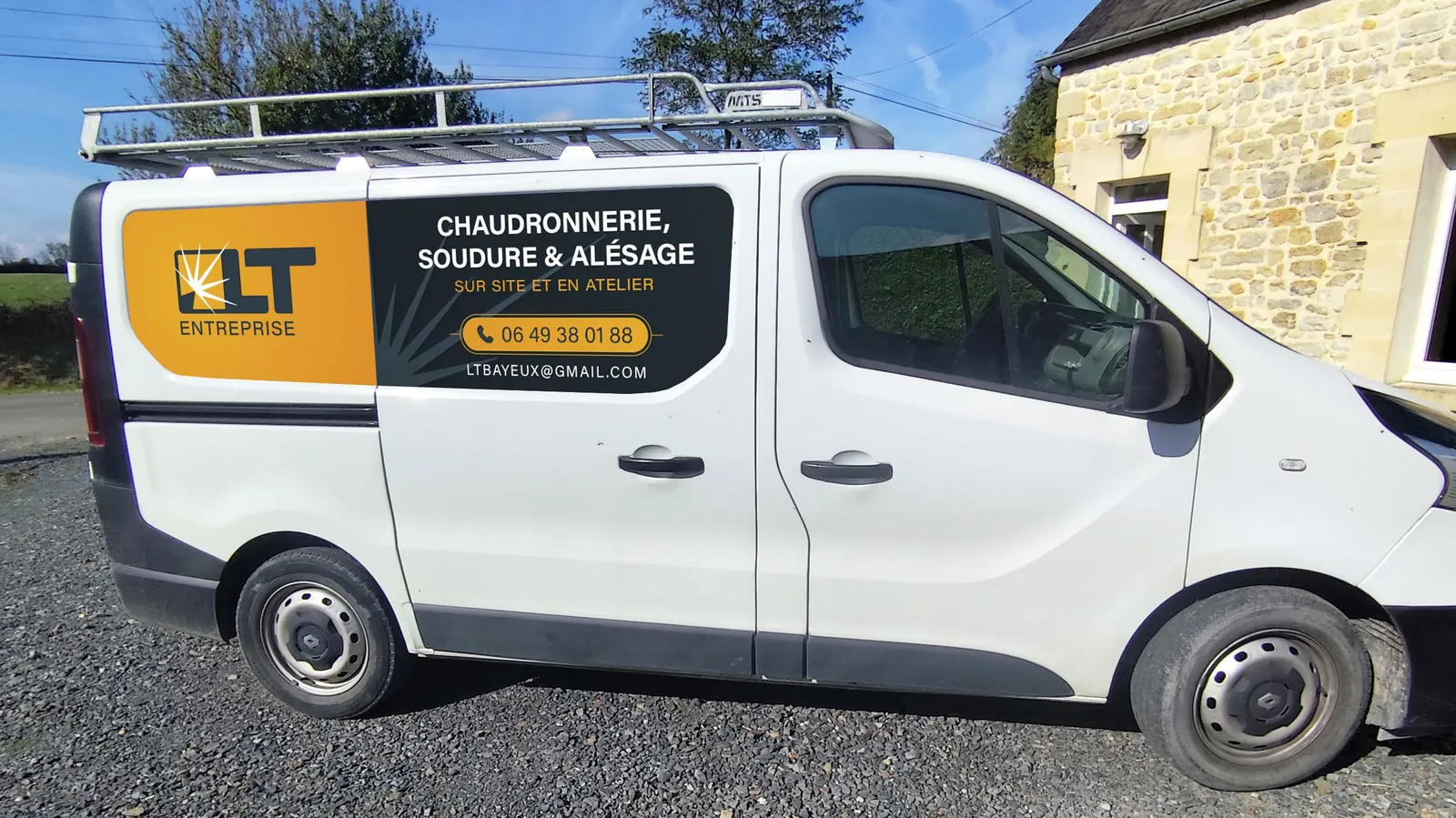 Utilitaire Renault Trafic blanc floqué LT Entreprise : panneau orange et bleu nuit « Chaudronnerie, soudure & alésage »