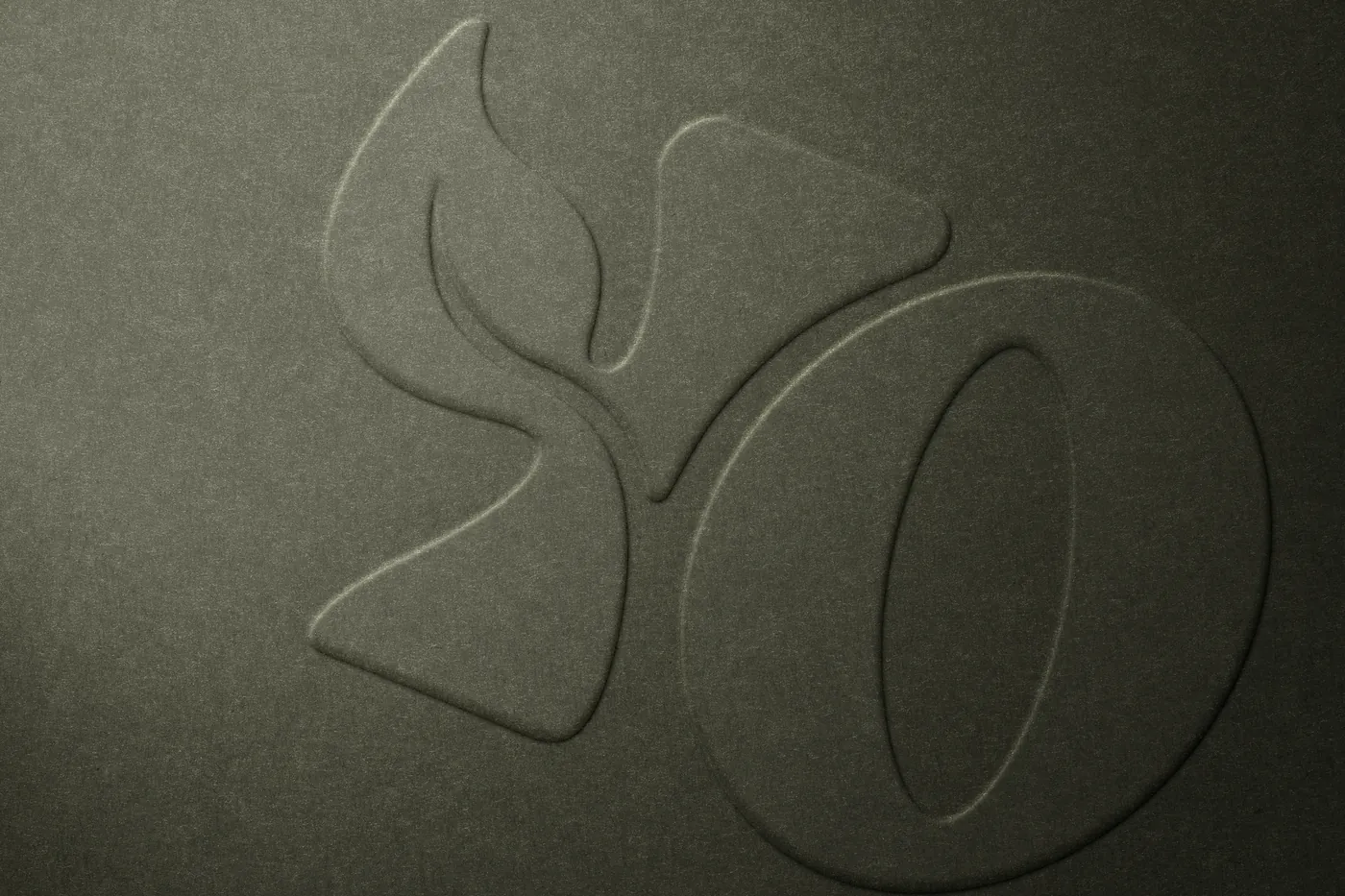 Gros plan d'un papier vert olive gaufré du Y en pousse et du O du logo YOU, en lumière rasante